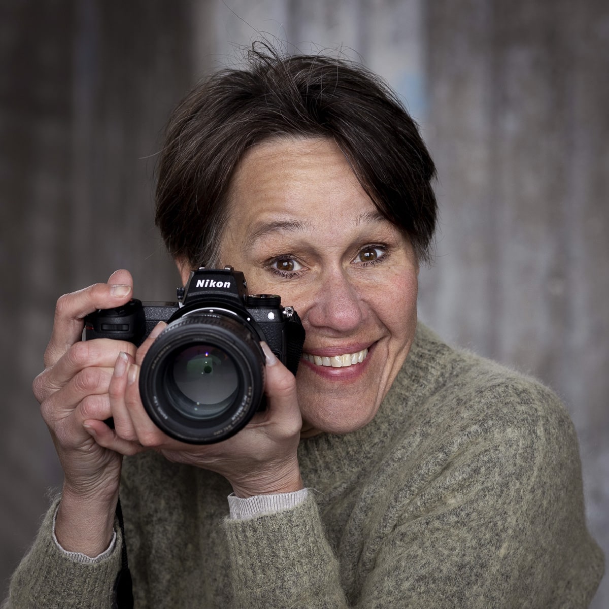 En kvinna som ler medan hon håller en kamera.